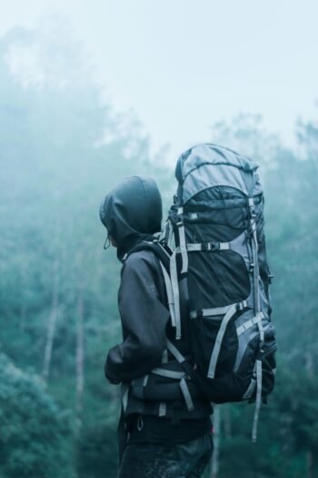 Man Wearing Black Hoodie Carries Black and Gray Backpacker Near Trees during Foggy Weather 'Discover the Magic of Sri Lanka