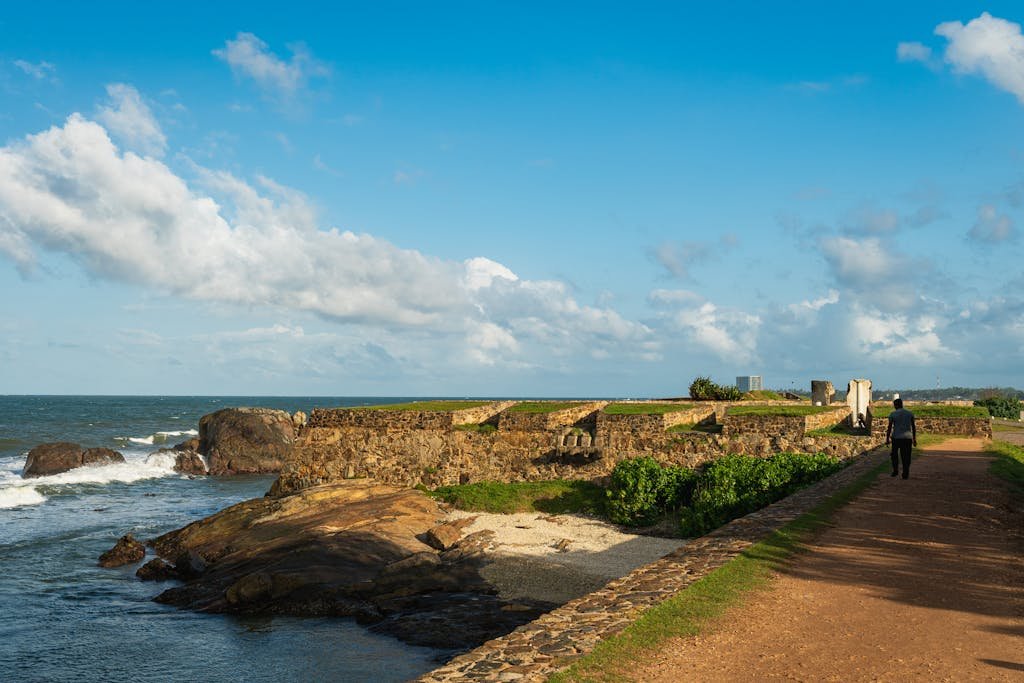 A path leading to the ocean with a lighthouse in the background