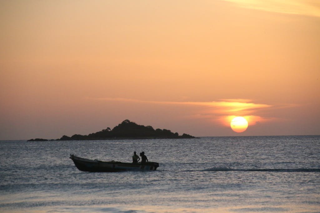 People Riding a Boat on the Ocean during Sunset