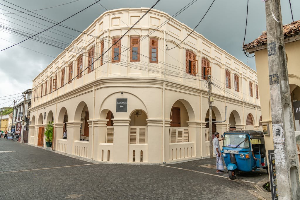 A historic colonial building in Galle, Sri Lanka with a vibrant blue tuk-tuk parked nearby.Galle Day Trip: Unveiling the Timeless Charm of Sri Lanka's Coastal Jewel..